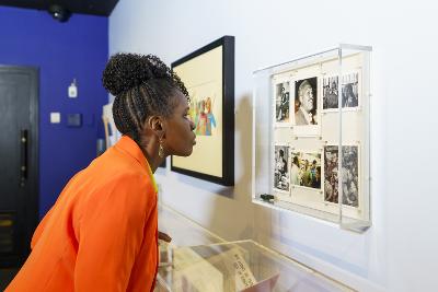 Photograph of a person looking at photographs which are pinned to a backing