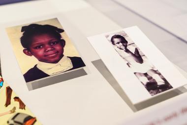 Photograph of objects in the exhibition: two photographs of Malorie Blackman as a child are shown in a glass case.